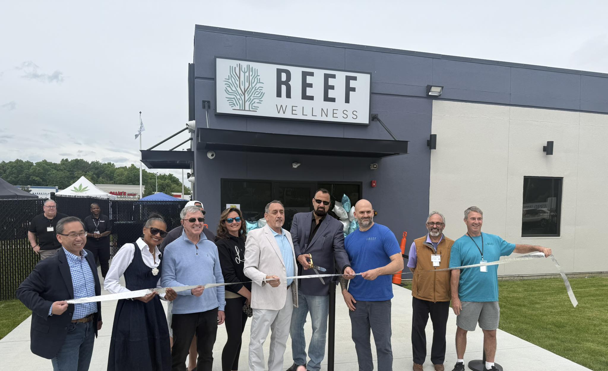Mayor Chris Beauchamp, center, store owners and others cut the ribbon to open Reef Wellness on Sunday.