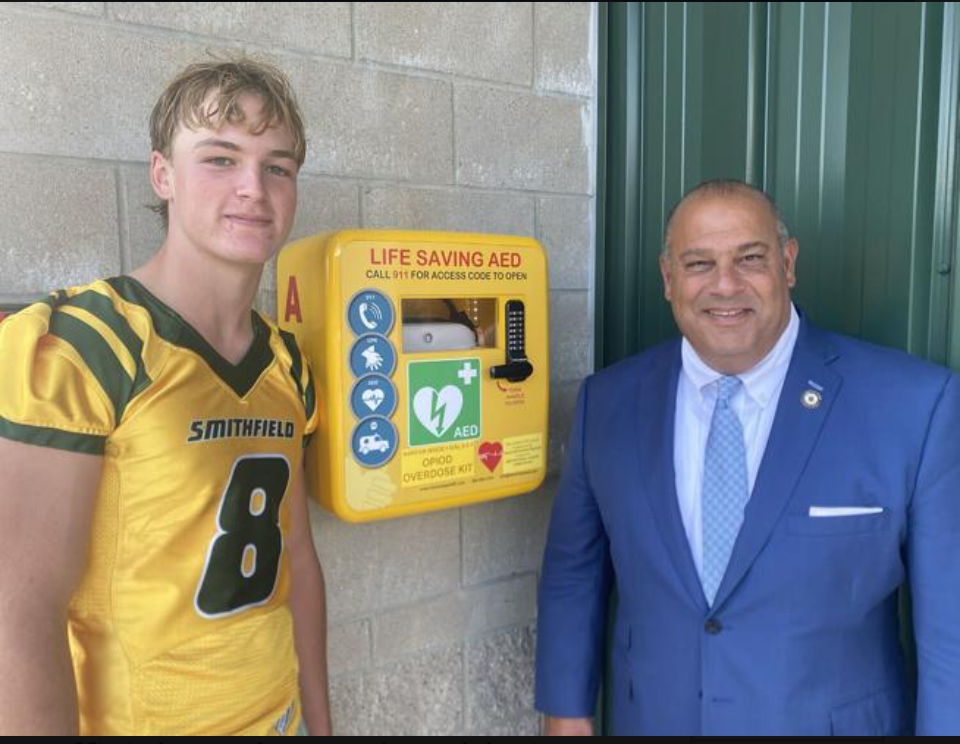 Sen. David Tikoian with the two AEDs he contributed to Smithfield High School.