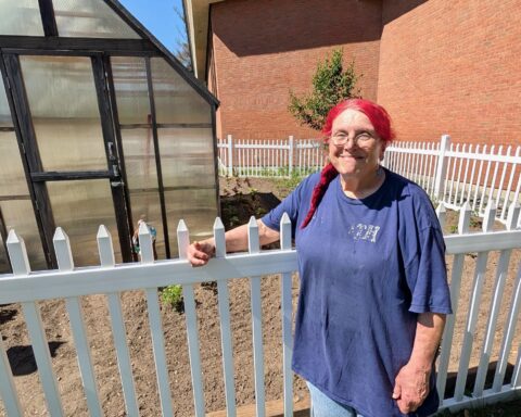 Adrienne Marchetti stands next to the garden where she grows much of the food she uses in her cooking.
