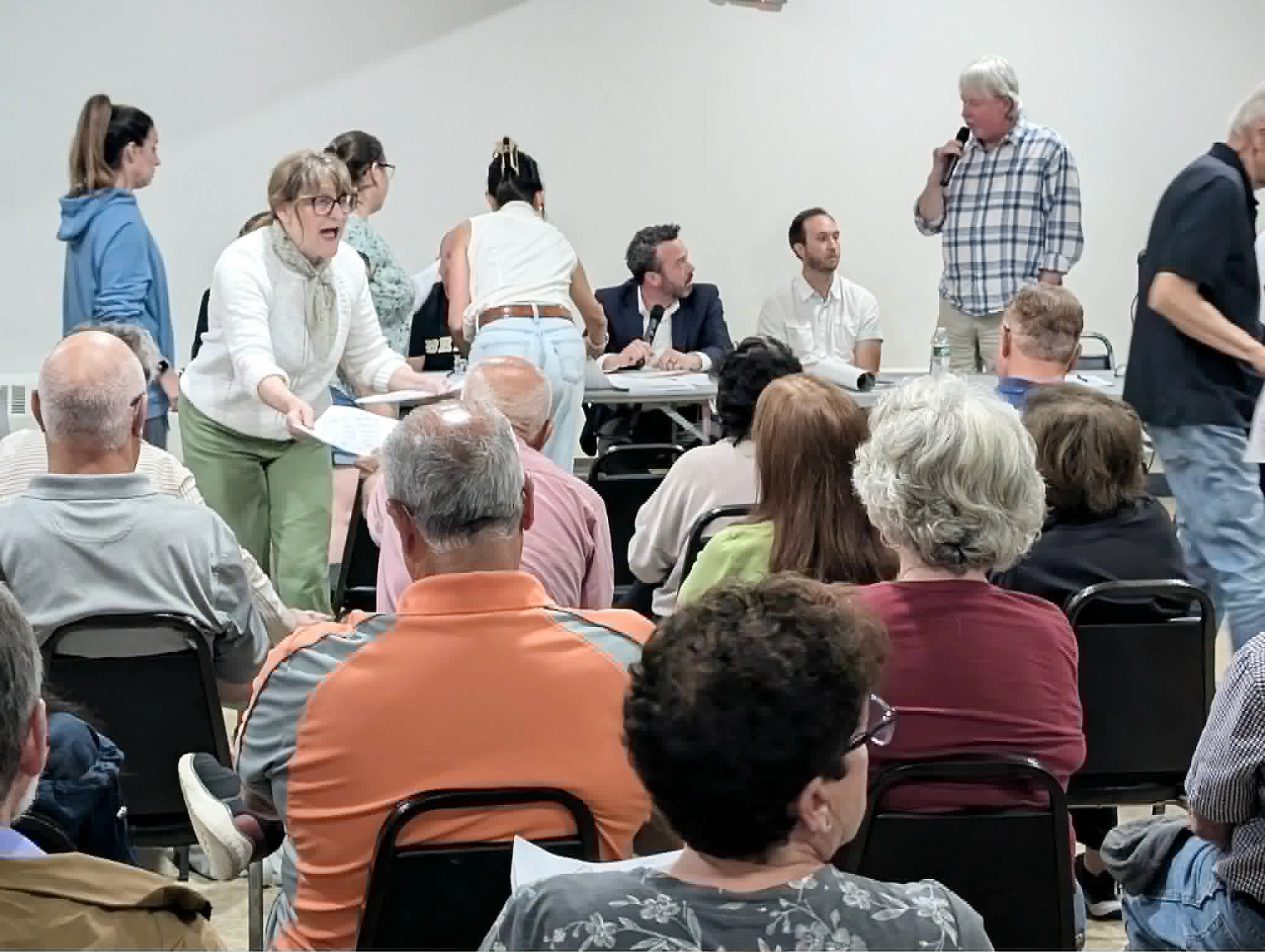 Andy Brown, right, questions Dylan Conley and Brad Clark as residents come up to the table to get the latest version of plans for 28 homes off Wilbur Road on Monday.
