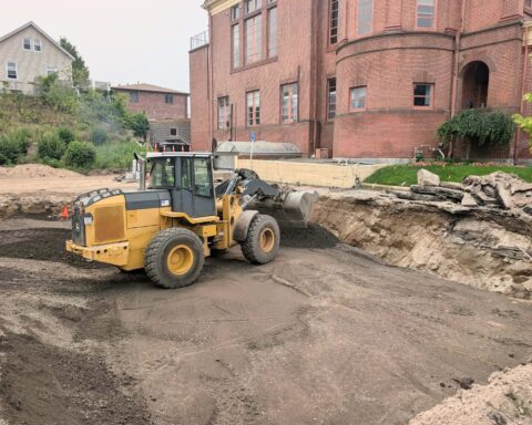 A heavy machine operator brings new dirt into the hole next to Cumberland Town Hall.