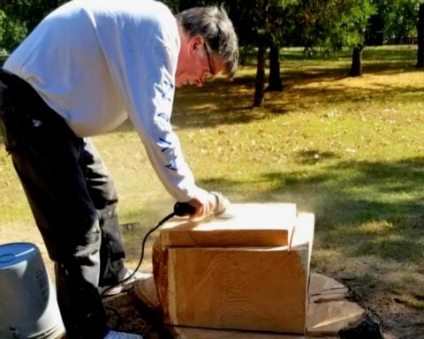 Tom Rogers carves and sands a chess board into a stump at Slater Park.