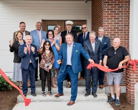 Town Administrator Phil Gould, surrounded by elected officials, cuts the ribbon to officially open the new facility.