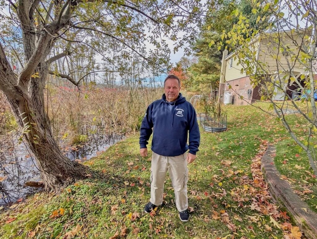 Steve Bacon stands in the narrowing stretch of land between his home on Nate Whipple Highway and the expanding Sneech Pond Brook. (Insider photos by Ethan Shorey).