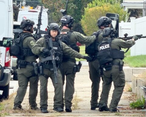 Officers respond with guns drawn on Rowe Avenue in Pawtucket Monday.